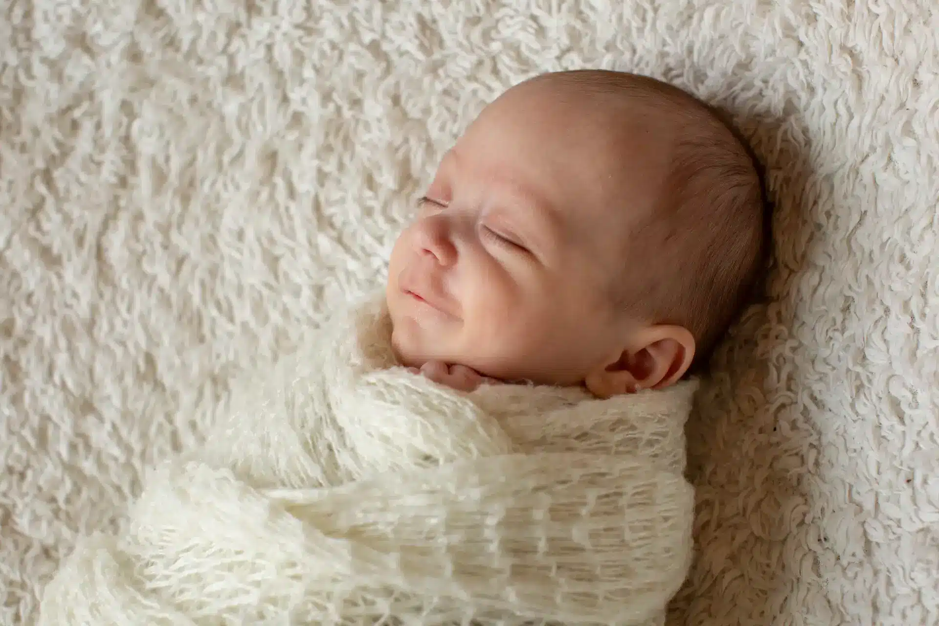 Bébé souriant aux anges dans son sommeil, studio photo nouveau-né Brabant Wallon