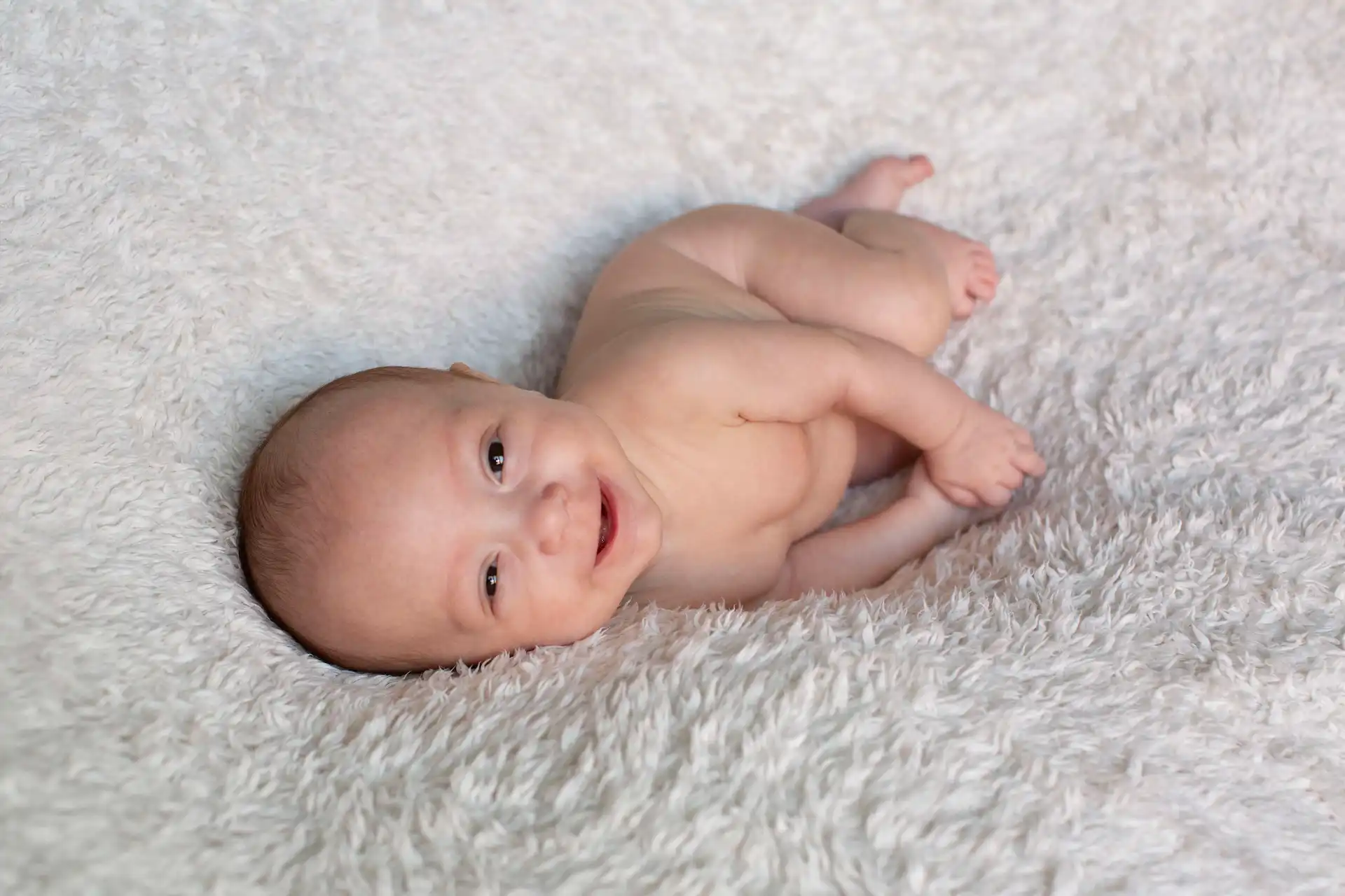 Regard rieur et éveillé d'un bébé nouveau-né, séance photo studio Brabant Wallon