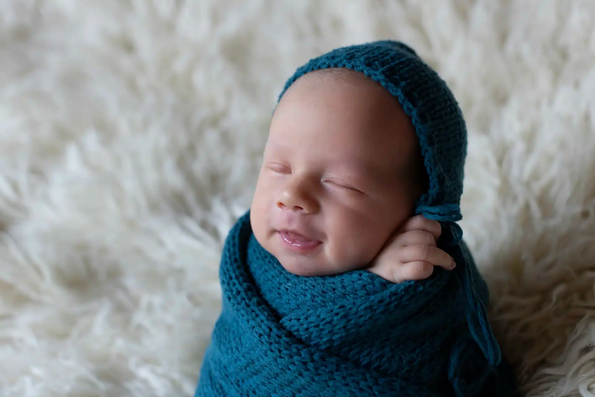 Petit visage niché dans un lange doux, séance photo nouveau-né en studio