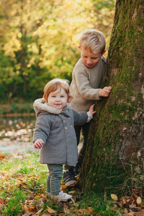 Frère et soeur jouant dans la campagne du brabant wallon lors d'un shooting photo en famille