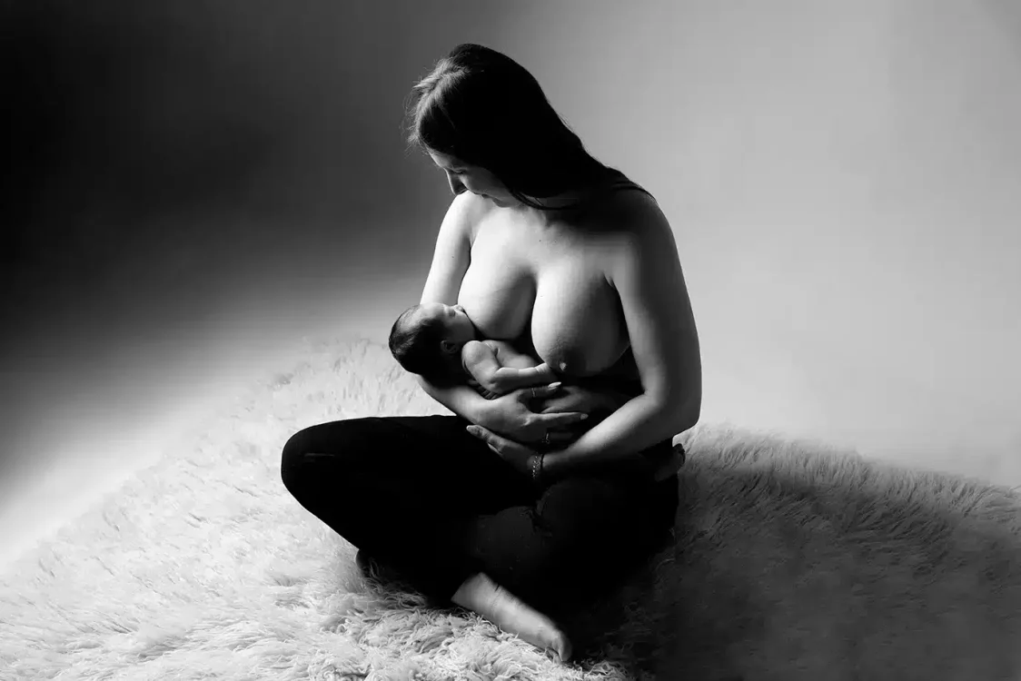 Moment d'allaitement capturé avec pudeur lors d'une séance photo nouveau-né en studio