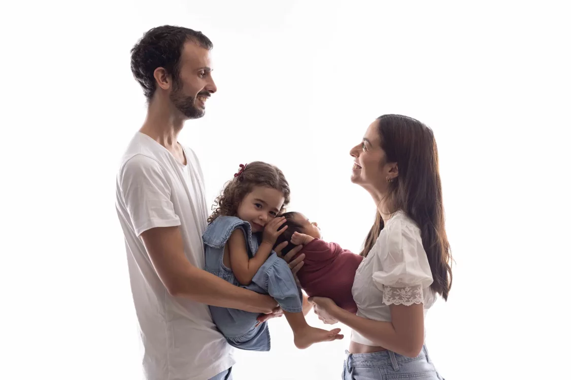 Portrait de famille réunissant parents, aîné et nouveau-né, séance photo en studio à Court-Saint-Étienne