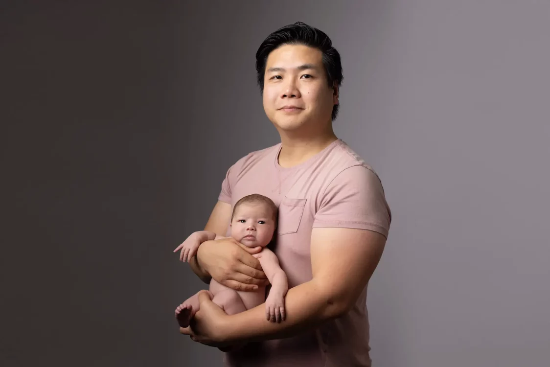 Papa tenant fièrement son nouveau-né contre lui, séance photo en studio