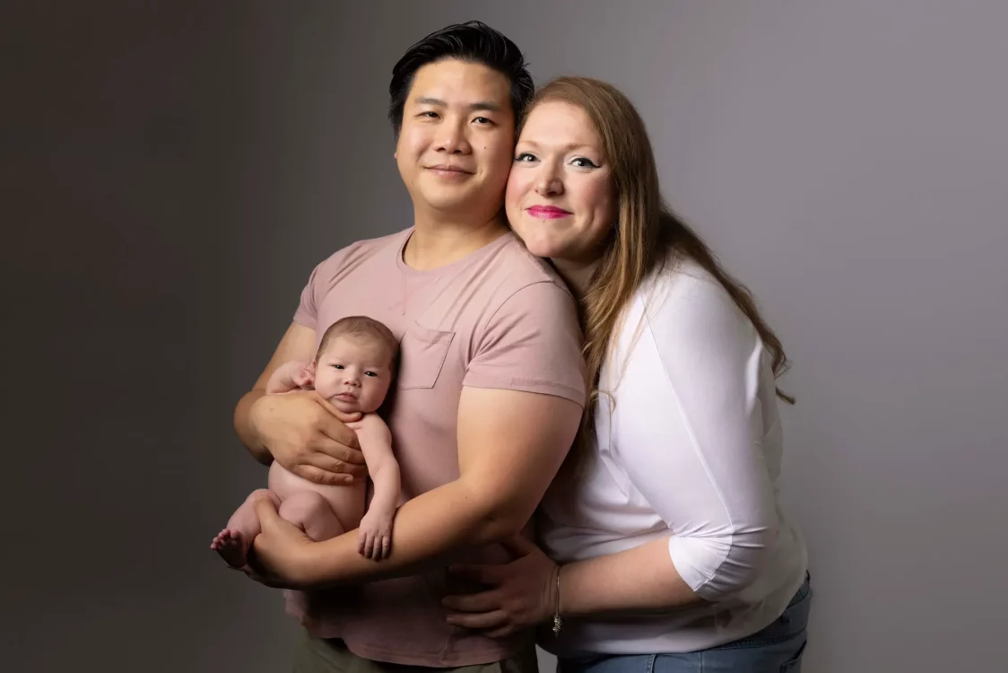Portrait de famille avec le nouveau-né dans les bras de ses deux parents, séance photo en studio