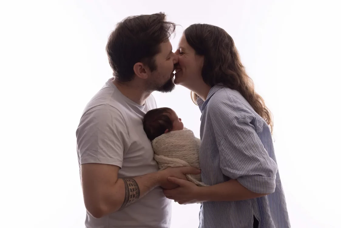 Papa et maman enlaçant leur nouveau-né, séance photo nouveau-né en studio à Court-Saint-Étienne