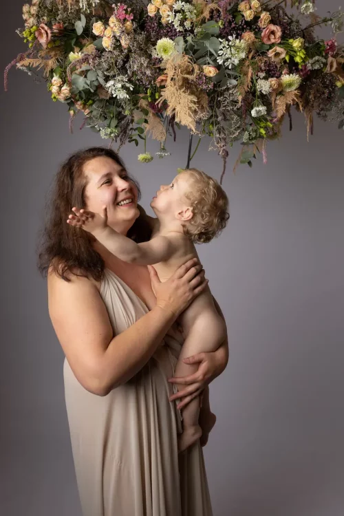 Séance photo en studio d'une maman avec son bébé en studio avec un parasol fleuri