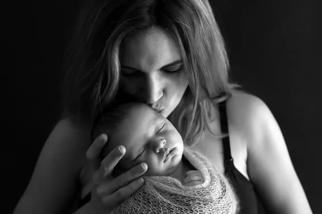 Jeune maman tenant tendrement son nouveau-né dans les bras, séance photo nouveau-né en studio à Court-Saint-Étienne